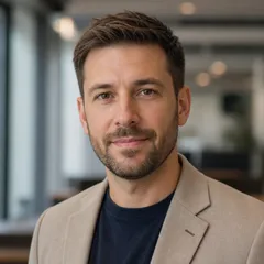 A professional author portrait featuring a neutral-looking adult in smart casual attire, set against a softly blurred office 